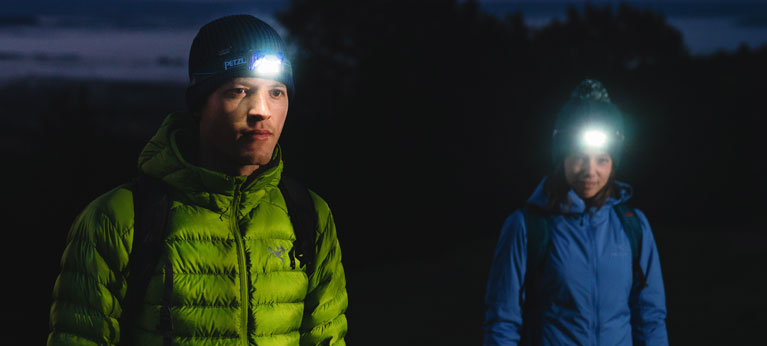 Two hikers walking in the dark with head torches on